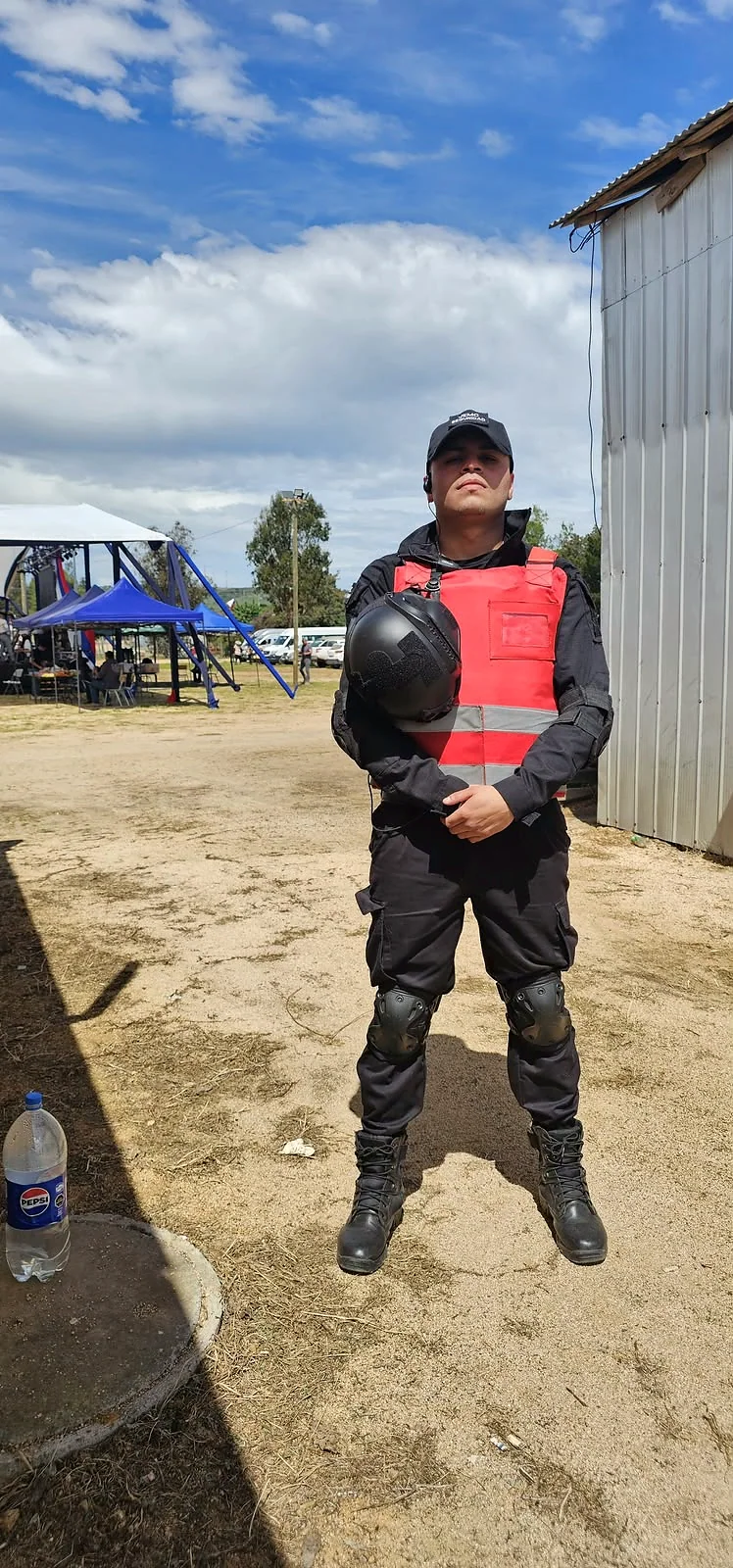 Guardia de seguridad con casco y chaleco rojo en una instalación exterior