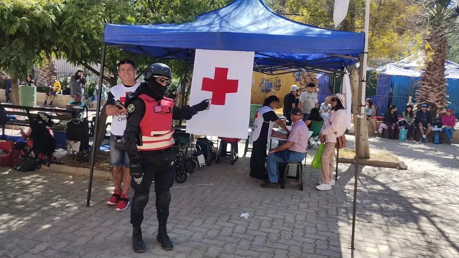 Guardia equipado frente a carpa de Cruz Roja en un evento al aire libre