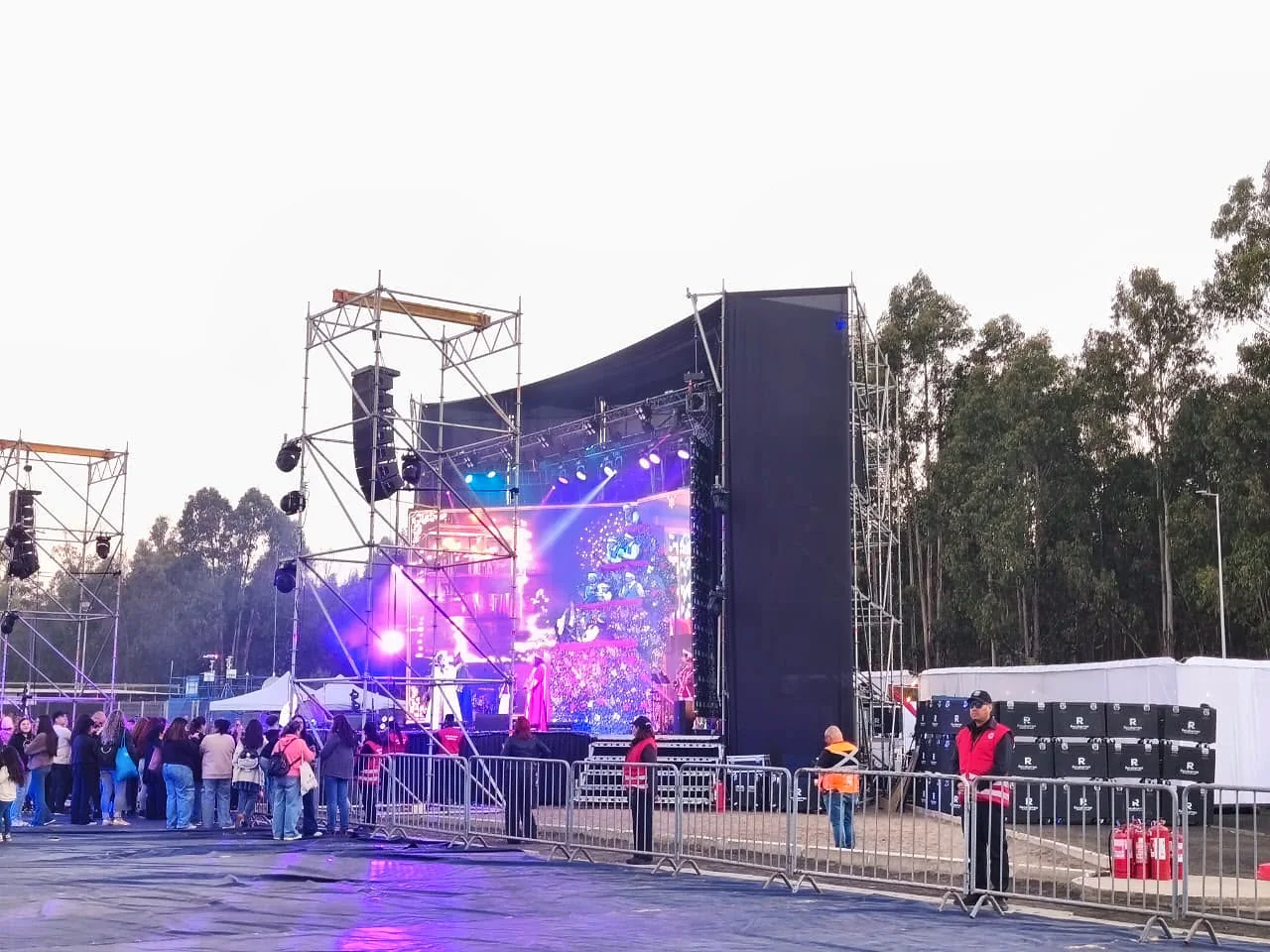 Guardia vigilando el perímetro cercado de un escenario con luces violetas