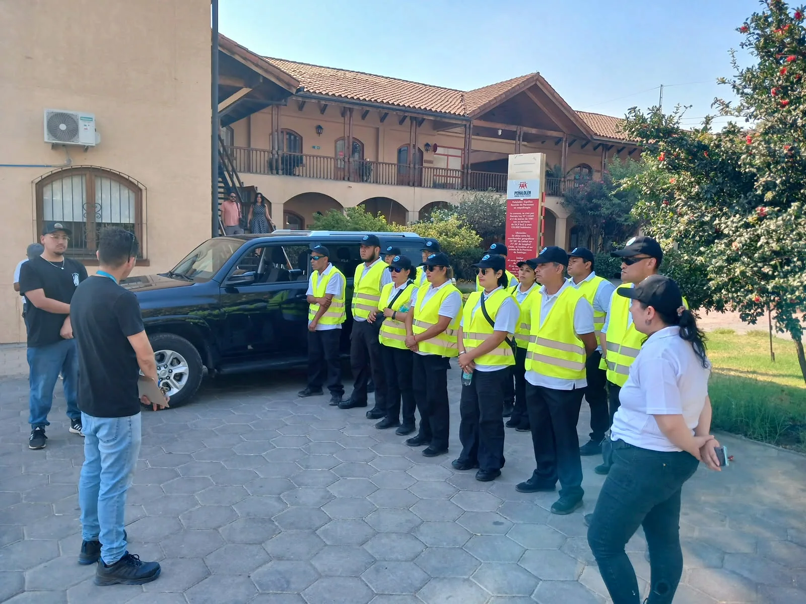 Equipo con chalecos amarillos escucha instrucciones junto a vehículo