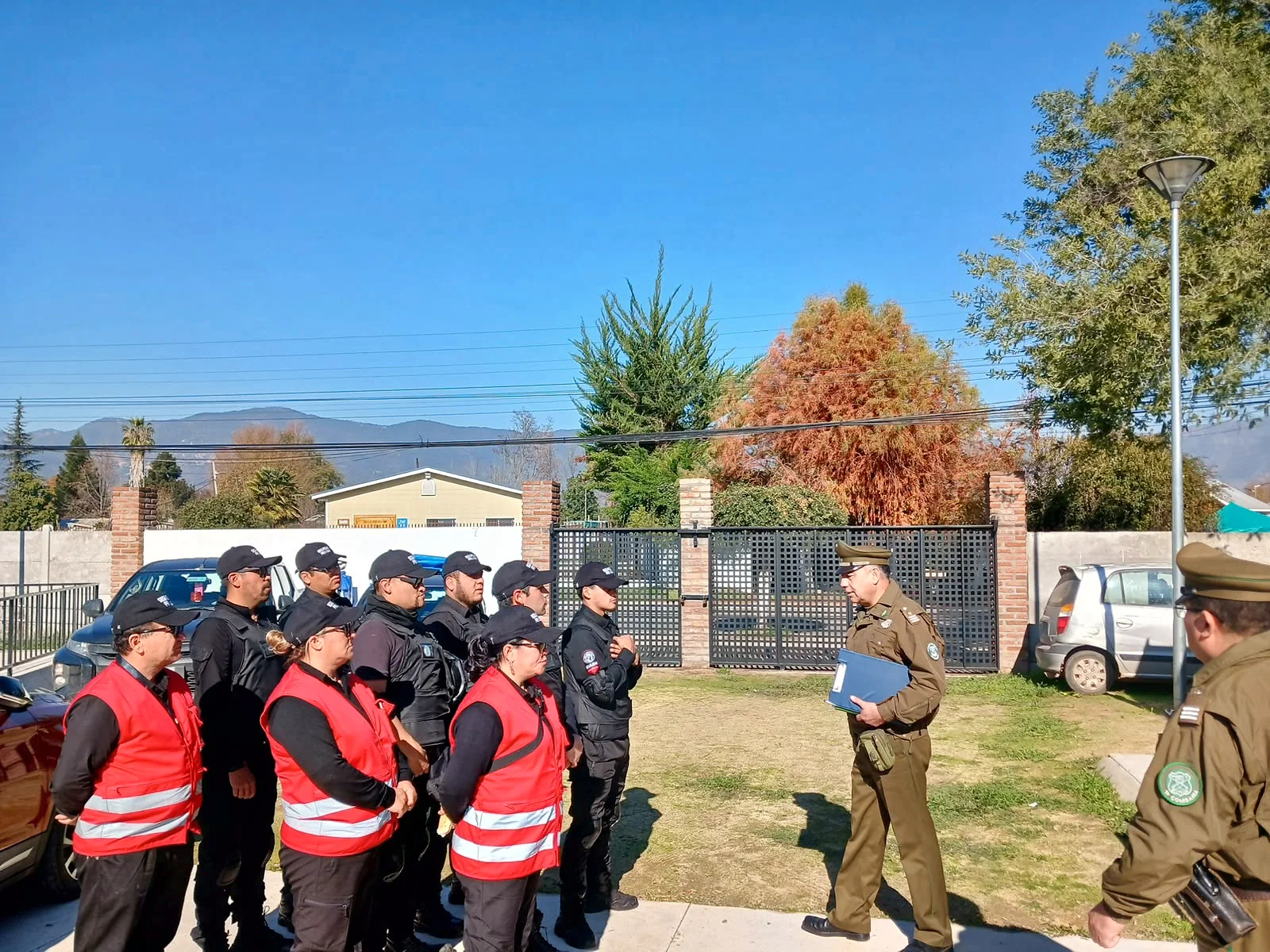Guardias con chalecos rojos escuchando a un funcionario policial